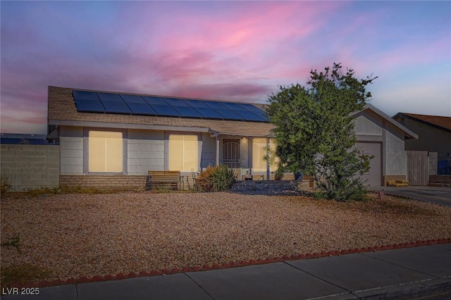 single story home with entry steps, a garage, fence, concrete driveway, and roof mounted solar panels