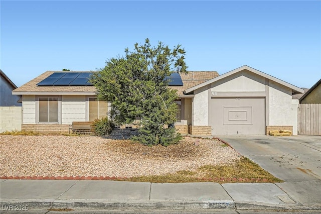 view of front of home featuring brick siding, fence, solar panels, and stucco siding