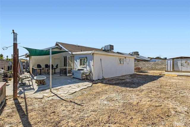 back of property with central AC unit, a storage shed, an outdoor structure, fence, and a patio area