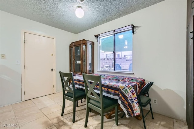 dining area with a textured ceiling and light tile patterned flooring