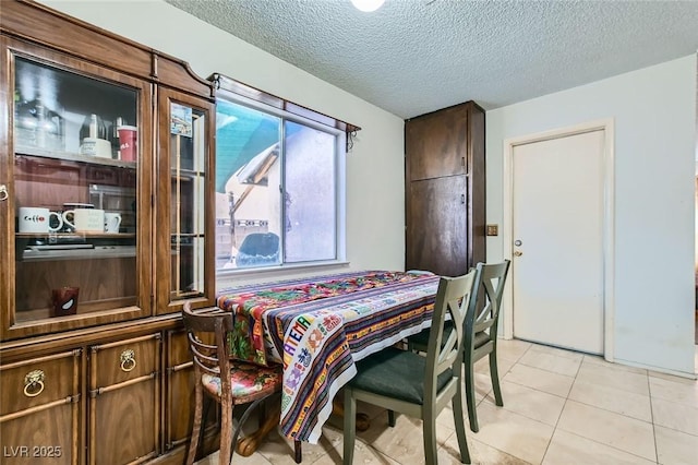 dining area with a textured ceiling and light tile patterned flooring