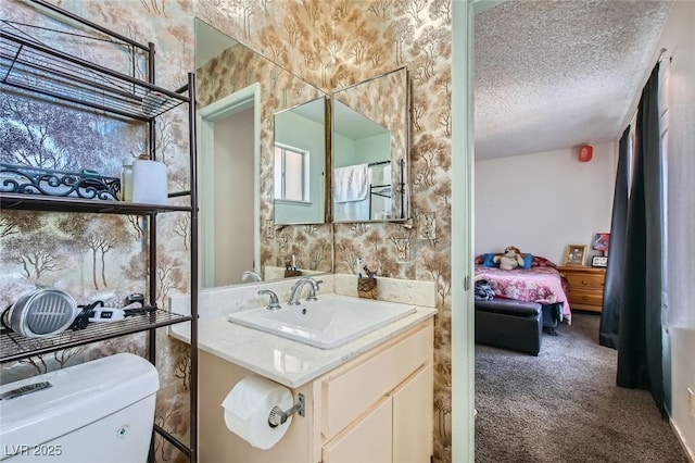 ensuite bathroom featuring a textured ceiling, toilet, vanity, and ensuite bathroom