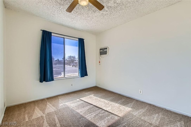 spare room featuring a textured ceiling, carpet floors, a ceiling fan, baseboards, and an AC wall unit