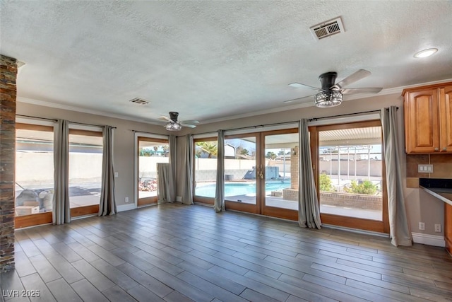 interior space featuring ceiling fan, crown molding, visible vents, and wood finished floors