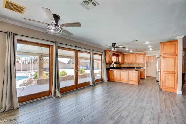 kitchen with freestanding refrigerator, light wood finished floors, visible vents, and crown molding