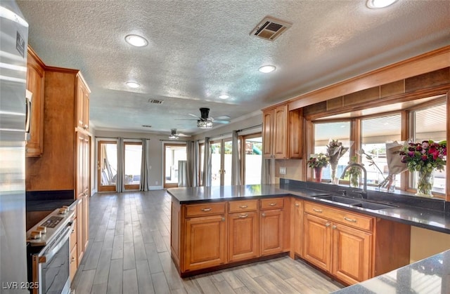 kitchen featuring a sink, visible vents, brown cabinetry, and electric stove