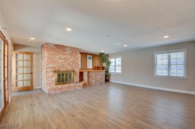 unfurnished living room with recessed lighting, visible vents, a brick fireplace, wood finished floors, and baseboards