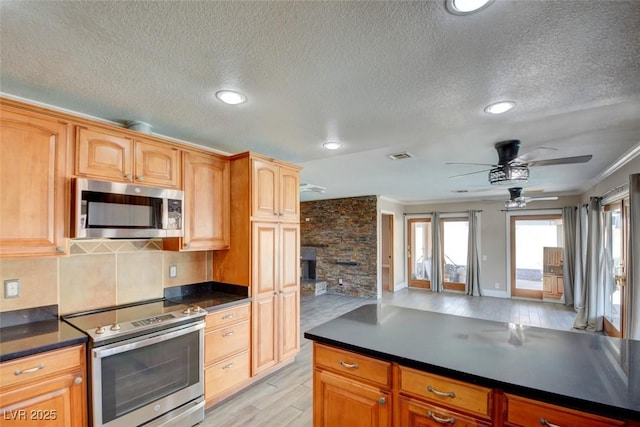 kitchen with stainless steel appliances, dark countertops, crown molding, and light wood finished floors