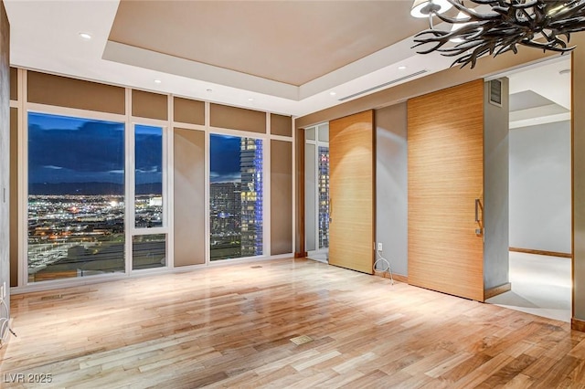 3750 Las Vegas Blvd Unit 2711, Las Vegas, NV 89158 - spare room featuring a raised ceiling, recessed lighting, wood finished floors, expansive windows, and a chandelier
