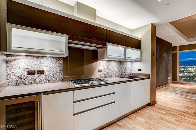 3750 Las Vegas Blvd Unit 2711, Las Vegas, NV 89158 - kitchen featuring beverage cooler, gas cooktop, white cabinets, light wood finished floors, and decorative backsplash