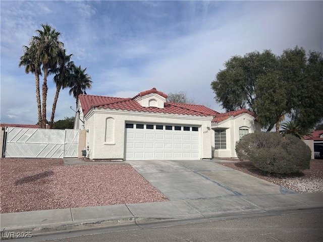 mediterranean / spanish home with stucco siding, driveway, an attached garage, and a tile roof