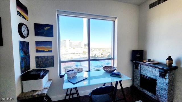 interior space with baseboards, a stone fireplace, visible vents, and a city view