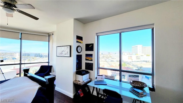 bedroom with a view of city, multiple windows, wood finished floors, and baseboards