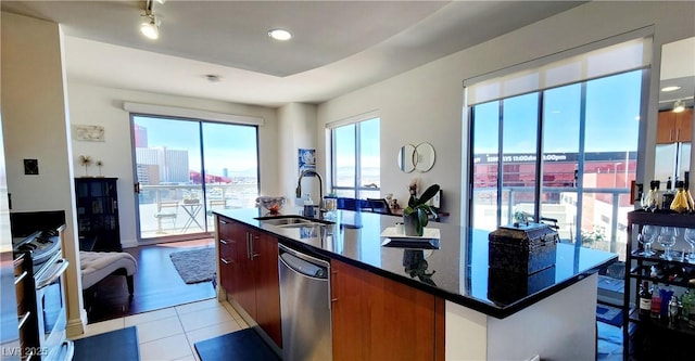 kitchen with light tile patterned floors, a sink, appliances with stainless steel finishes, an island with sink, and modern cabinets