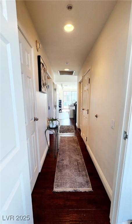 hallway featuring dark wood-style floors and baseboards