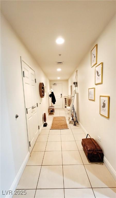 hall featuring light tile patterned flooring, visible vents, and baseboards