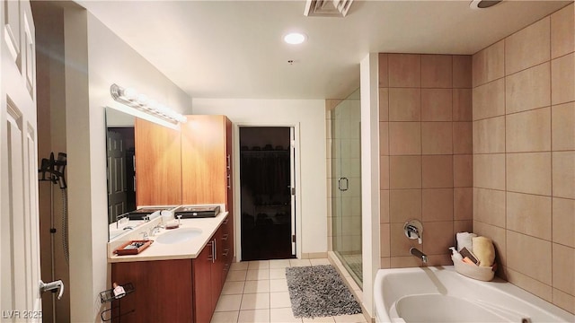 bathroom featuring a walk in closet, a garden tub, a stall shower, vanity, and tile patterned flooring