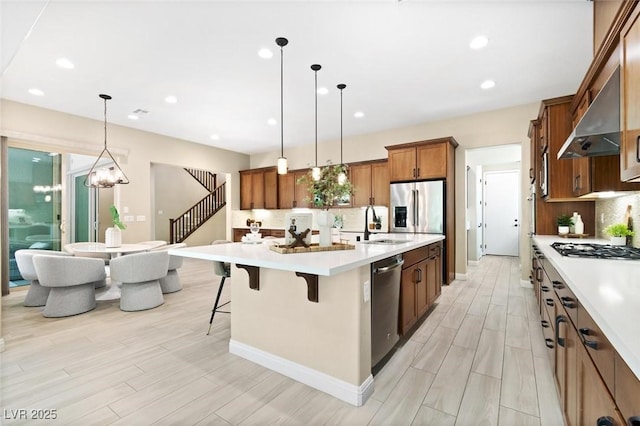 kitchen featuring brown cabinets, a breakfast bar area, stainless steel appliances, light countertops, and decorative backsplash