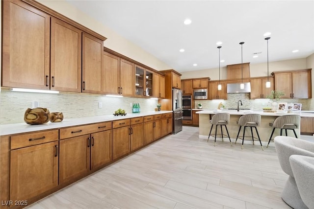 kitchen with light countertops, appliances with stainless steel finishes, a kitchen bar, and brown cabinets