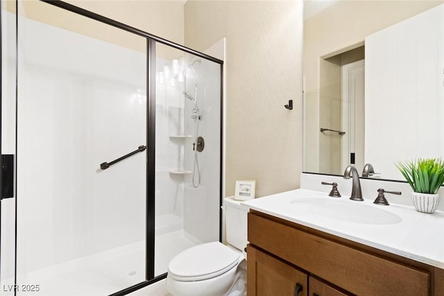 bathroom with a stall shower, vanity, and toilet