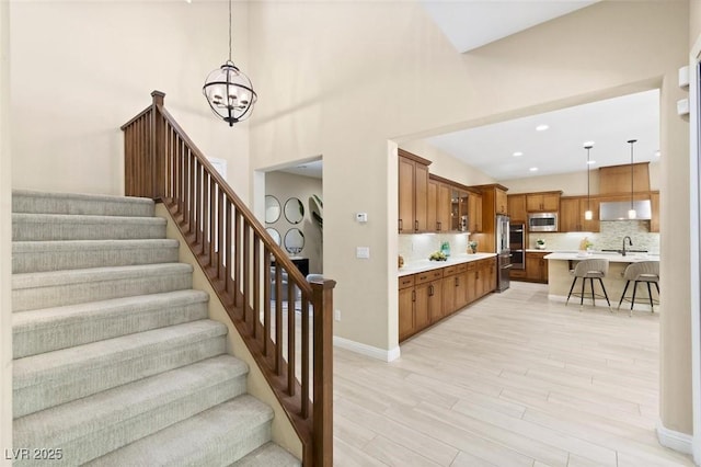 stairway with baseboards, a chandelier, wood finished floors, and recessed lighting