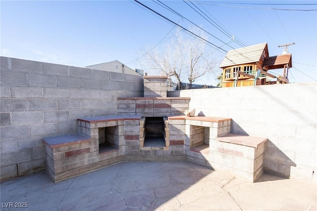 view of patio / terrace featuring exterior fireplace and fence