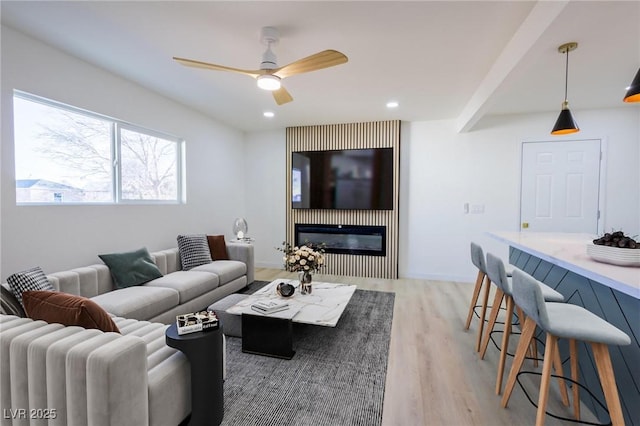 living room with recessed lighting, light wood-style floors, a glass covered fireplace, and a ceiling fan