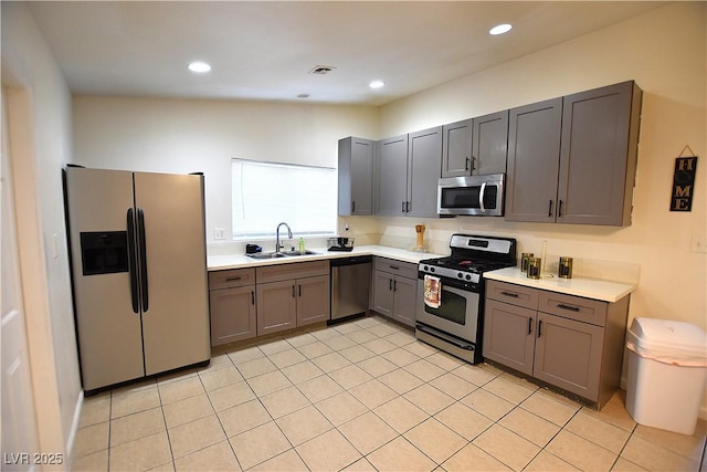 kitchen with stainless steel appliances, gray cabinets, light countertops, visible vents, and a sink