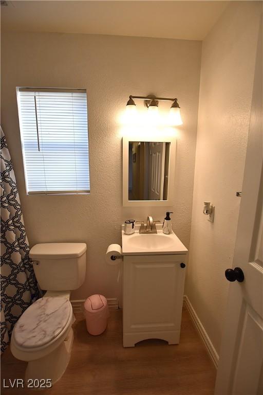 bathroom featuring baseboards, vanity, toilet, and wood finished floors