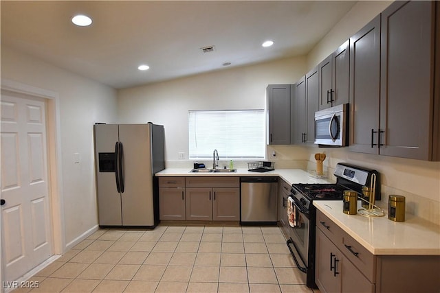 kitchen with appliances with stainless steel finishes, light countertops, a sink, and light tile patterned flooring