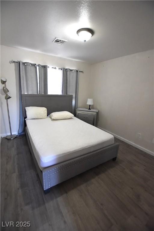 bedroom featuring baseboards, visible vents, and dark wood finished floors