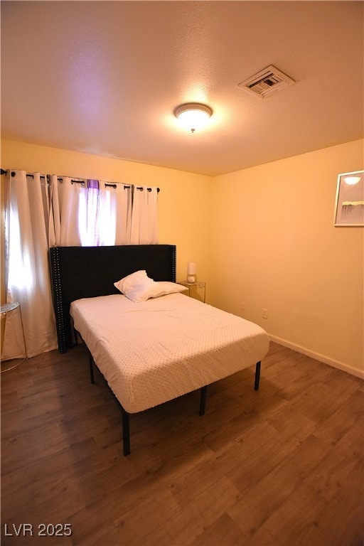 bedroom featuring dark wood finished floors, visible vents, and baseboards