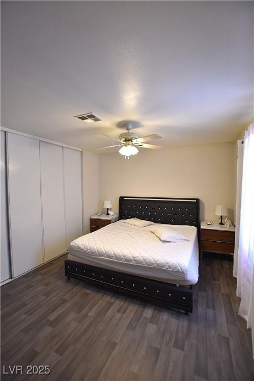 bedroom with dark wood-style floors, a ceiling fan, visible vents, and a closet