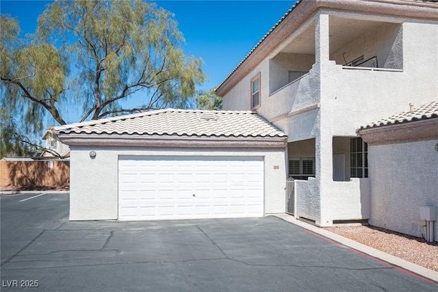 exterior space featuring a garage, a tiled roof, a balcony, and stucco siding