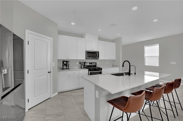 kitchen with a breakfast bar, a center island with sink, stainless steel appliances, and a sink