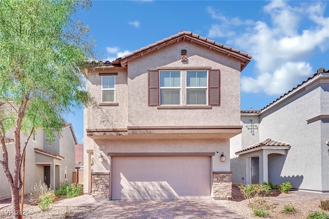 mediterranean / spanish-style home featuring stucco siding, stone siding, and an attached garage