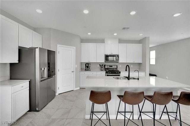 kitchen with a kitchen bar, visible vents, marble finish floor, a sink, and stainless steel appliances