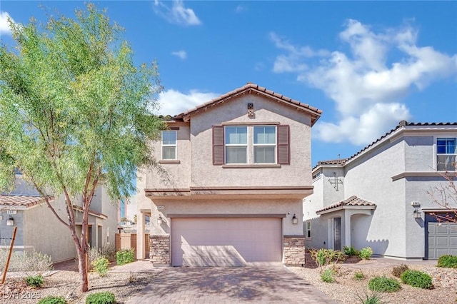 mediterranean / spanish-style home featuring an attached garage, stucco siding, stone siding, a tiled roof, and decorative driveway