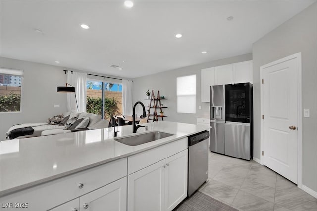 kitchen with marble finish floor, a sink, appliances with stainless steel finishes, white cabinets, and light countertops