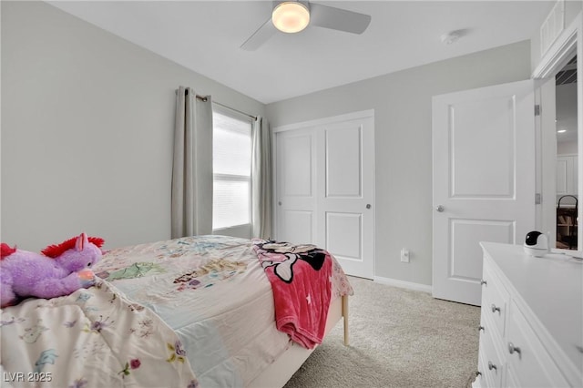 bedroom featuring a closet, light colored carpet, baseboards, and ceiling fan