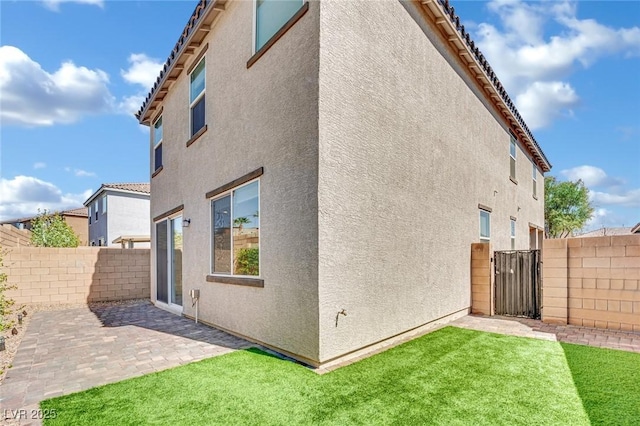 back of property with a patio, a yard, a fenced backyard, stucco siding, and a tiled roof