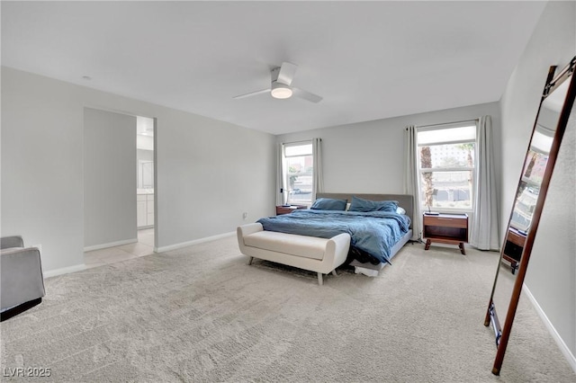 bedroom with a ceiling fan, light colored carpet, baseboards, and ensuite bathroom