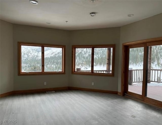 spare room featuring light wood-style floors, visible vents, and baseboards