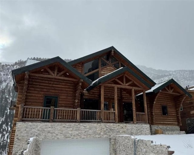 cabin featuring a garage, log siding, and a mountain view