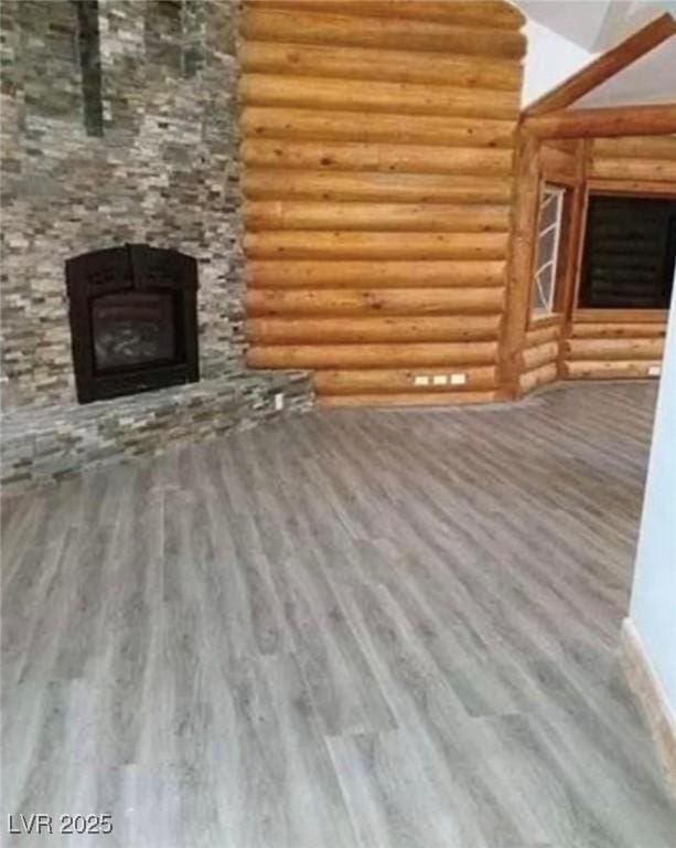 unfurnished living room featuring rustic walls, a fireplace, and wood finished floors