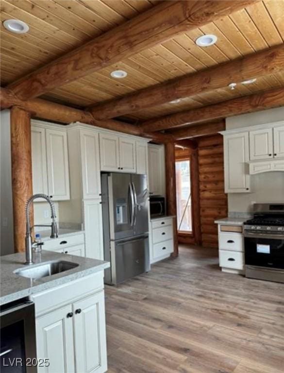 kitchen with appliances with stainless steel finishes, a sink, white cabinets, and light wood-style floors