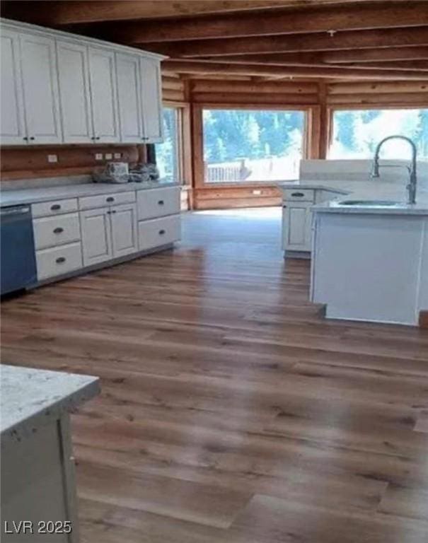 kitchen featuring a wealth of natural light, dishwasher, wood finished floors, white cabinetry, and a sink