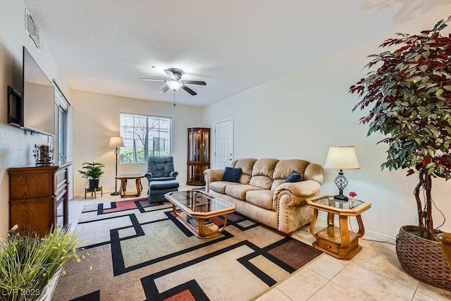 living area featuring visible vents, a ceiling fan, a textured ceiling, tile patterned flooring, and baseboards