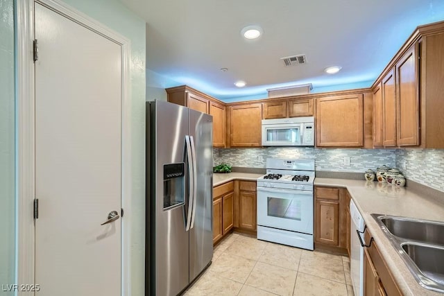 kitchen featuring a sink, white appliances, visible vents, and backsplash