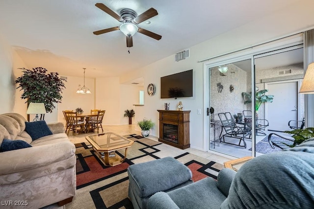 living area featuring ceiling fan, visible vents, and a glass covered fireplace